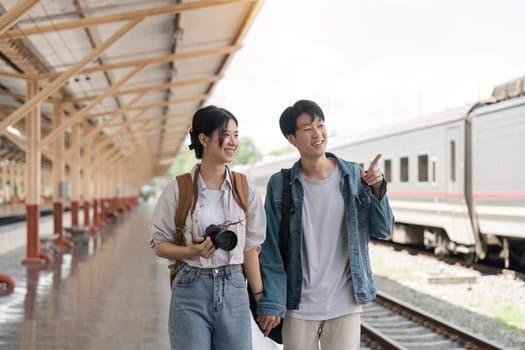 Beautiful couple at railway station waiting for the train. Young woman and man waiting to board a train.