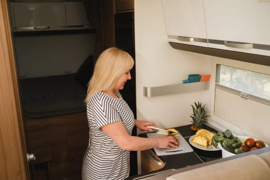 a woman cooking food in the kitchen inside a motorhome, the interior of a motorhome.