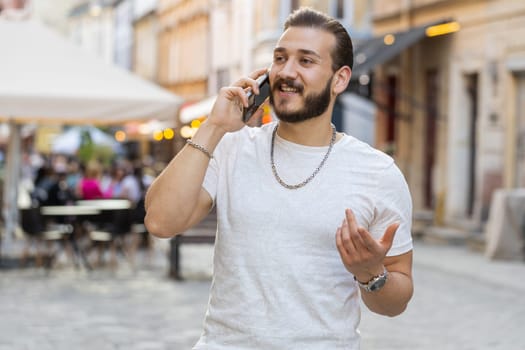 Portrait of man tourist having remote conversation communicate speaking by smartphone with friend, talking on phone unexpected good news gossip walking in urban city street. Town lifestyles outdoors