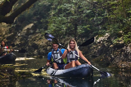 A group of friends enjoying having fun and kayaking while exploring the calm river, surrounding forest and large natural river canyons.