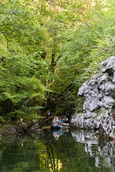 A young couple enjoying an idyllic kayak ride in the middle of a beautiful river surrounded by forest greenery.