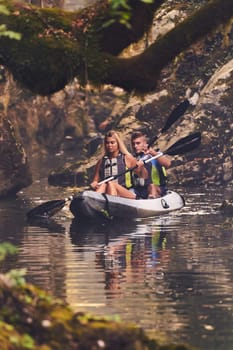 A young couple enjoying an idyllic kayak ride in the middle of a beautiful river surrounded by forest greenery.