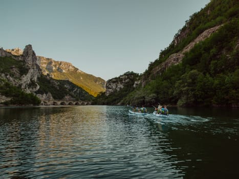 A group of friends enjoying having fun and kayaking while exploring the calm river, surrounding forest and large natural river canyons.