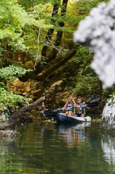 A young couple enjoying an idyllic kayak ride in the middle of a beautiful river surrounded by forest greenery.