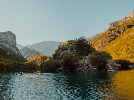 A group of friends enjoying having fun and kayaking while exploring the calm river, surrounding forest and large natural river canyons.