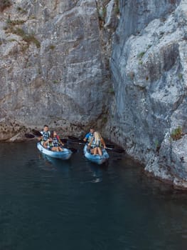 A group of friends enjoying fun and kayaking exploring the calm river, surrounding forest and large natural river canyons during an idyllic sunset