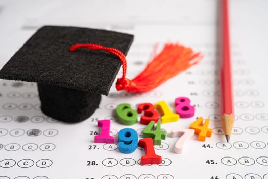 Graduation gap hat and pencil on answer sheet background : Education study testing learning teach concept.