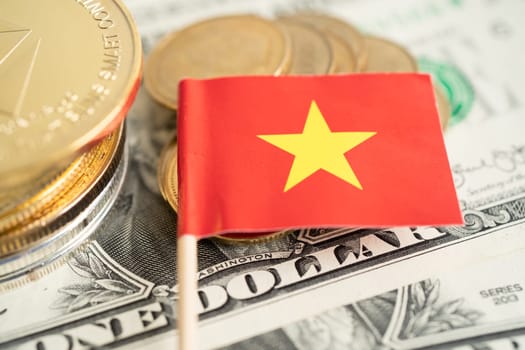 Stack of coins with Vietnam flag and US dollar banknotes.