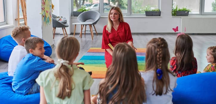 Reading time in an elementary school or kindergarten, a teacher reading a book to children in an elementary school or kindergarten. The concept of pre-school education. Selective focus.