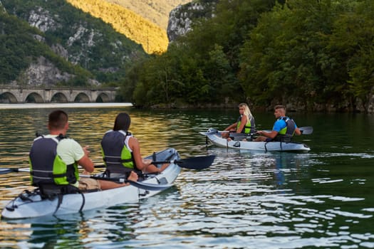 A group of friends enjoying having fun and kayaking while exploring the calm river, surrounding forest and large natural river canyons.