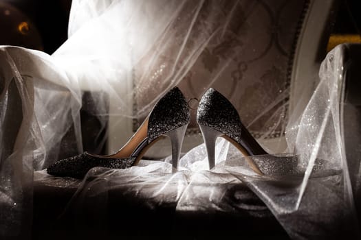 Golden rings of the newlyweds between white shoes with heels. Precious rings of the bride and groom