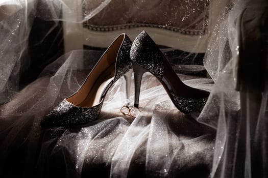 Golden rings of the newlyweds between white shoes with heels. Precious rings of the bride and groom