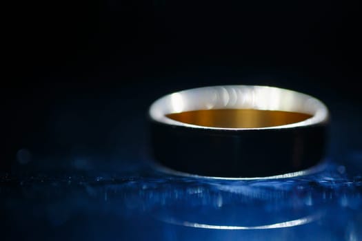 Gold wedding ring on black glass