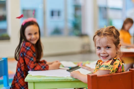 Creative kids during an art class in a daycare center or elementary school classroom drawing with female teacher