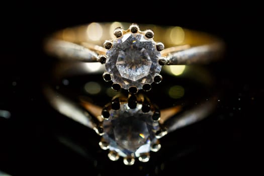 Gold wedding ring on black glass