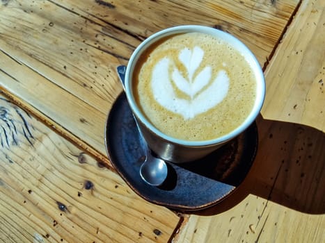Two cups of cappuccino with latte art on wooden background. Beautiful foam, greenery ceramic cups, stylish toning, place for text.