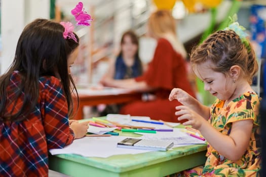 Creative kids during an art class in a daycare center or elementary school classroom drawing with female teacher