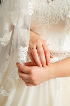 Bride's hands folded on a white wedding dress