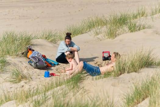 The Hague, Netherlands - April 2023. A family with a small child is relaxing on a sandy beach in the dunes. Sunny day in Holland.