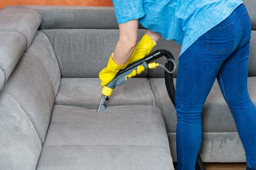 Cleaning concept. Woman washes soft furniture in living room. Employee removing dirt from furniture, closeup