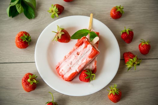 cooked homemade strawberry ice cream on a stick in a plate with strawberries