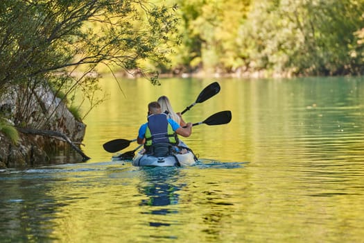 A young couple enjoying an idyllic kayak ride in the middle of a beautiful river surrounded by forest greenery.