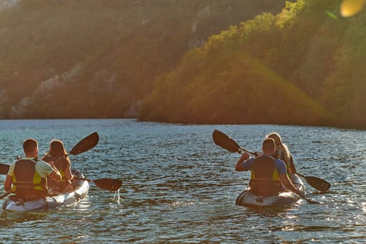 A group of friends enjoying fun and kayaking exploring the calm river, surrounding forest and large natural river canyons during an idyllic sunset