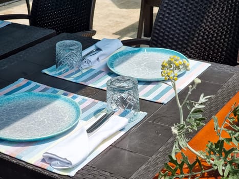 Tables with white tablecloth and chairs in restaurant, glasses and goblet on table.