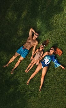 Top view of a happy family in swimsuits lying on the green grass.