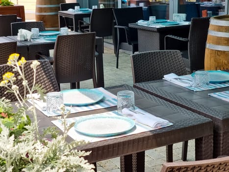 Tables with white tablecloth and chairs in restaurant, glasses and goblet on table.