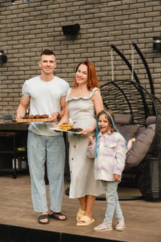 A happy family has prepared lunch and will eat at their house. Portrait of a family with food in their hands.