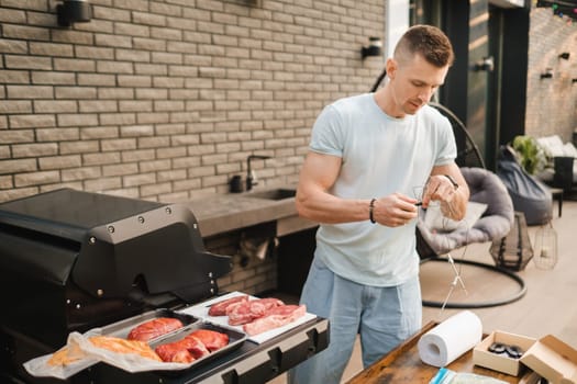 A man is preparing to cook meat on an open grill with temperature control.