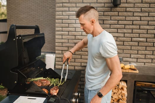 A man on the street is cooking a steak on the grill at a barbecue.