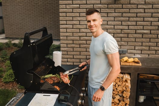 A man on the street is cooking a steak on the grill at a barbecue.