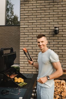 A man on the street is cooking a steak on the grill at a barbecue.