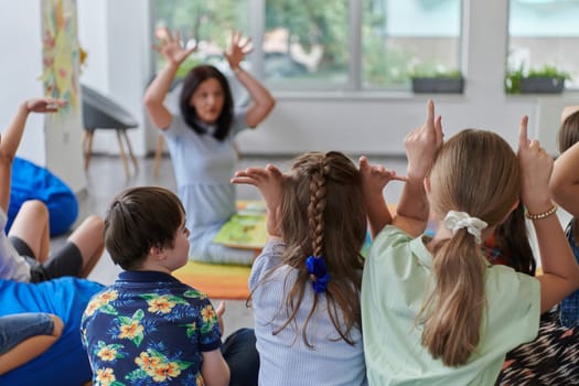 A happy female teacher sitting and playing hand games with a group of little schoolchildren.