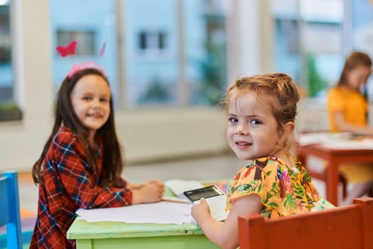 Creative kids during an art class in a daycare center or elementary school classroom drawing with female teacher