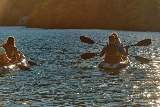 A group of friends enjoying fun and kayaking exploring the calm river, surrounding forest and large natural river canyons during an idyllic sunset