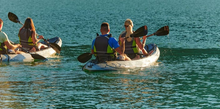 A group of friends enjoying fun and kayaking exploring the calm river, surrounding forest and large natural river canyons during an idyllic sunset