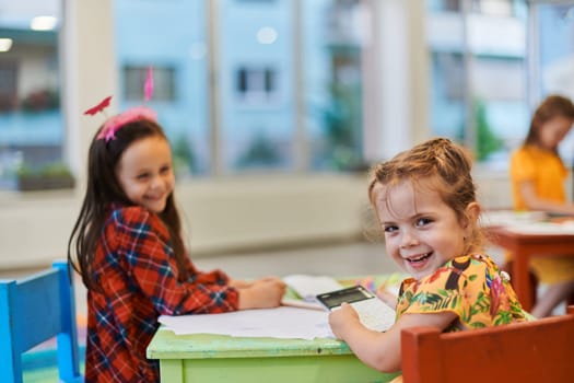 Creative kids during an art class in a daycare center or elementary school classroom drawing with female teacher