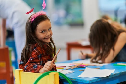 Creative kids during an art class in a daycare center or elementary school classroom drawing with female teacher