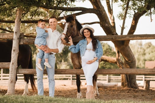 Happy family near horses at a farmer's ranch at sunset.