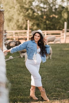 Stylish pregnant woman in a white hat in the countryside.