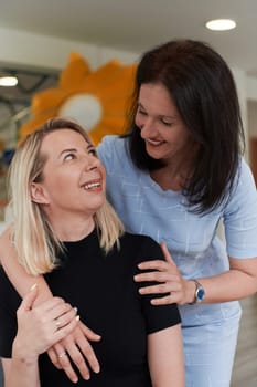 Two women share a heartfelt embrace while at a preschool, showcasing the nurturing and supportive environment for learning and growth.