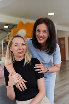 Two women share a heartfelt embrace while at a preschool, showcasing the nurturing and supportive environment for learning and growth.