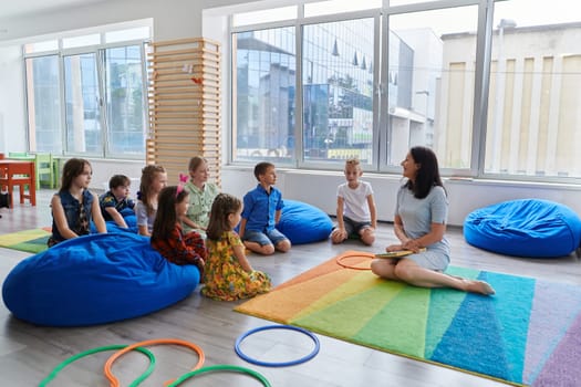 Reading time in an elementary school or kindergarten, a teacher reads a book to children in an elementary school or kindergarten. The concept of pre-school education. Selective focus.