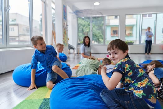 A happy female teacher sitting and playing hand games with a group of little schoolchildren.