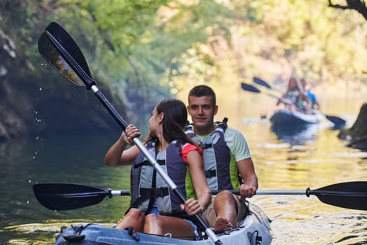 A group of friends enjoying having fun and kayaking while exploring the calm river, surrounding forest and large natural river canyons.