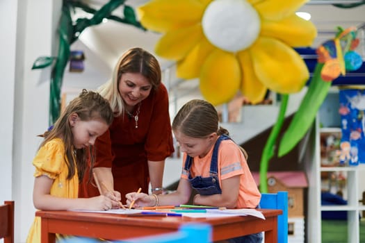 Creative kids during an art class in a daycare center or elementary school classroom drawing with female teacher