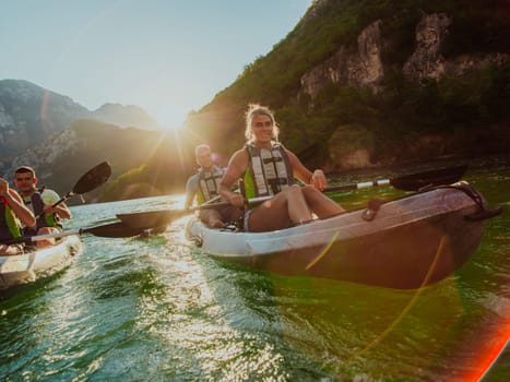 A group of friends enjoying fun and kayaking exploring the calm river, surrounding forest and large natural river canyons during an idyllic sunset